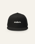 Black melowear endure. trucker cap from the front, wordmark printed on the panel